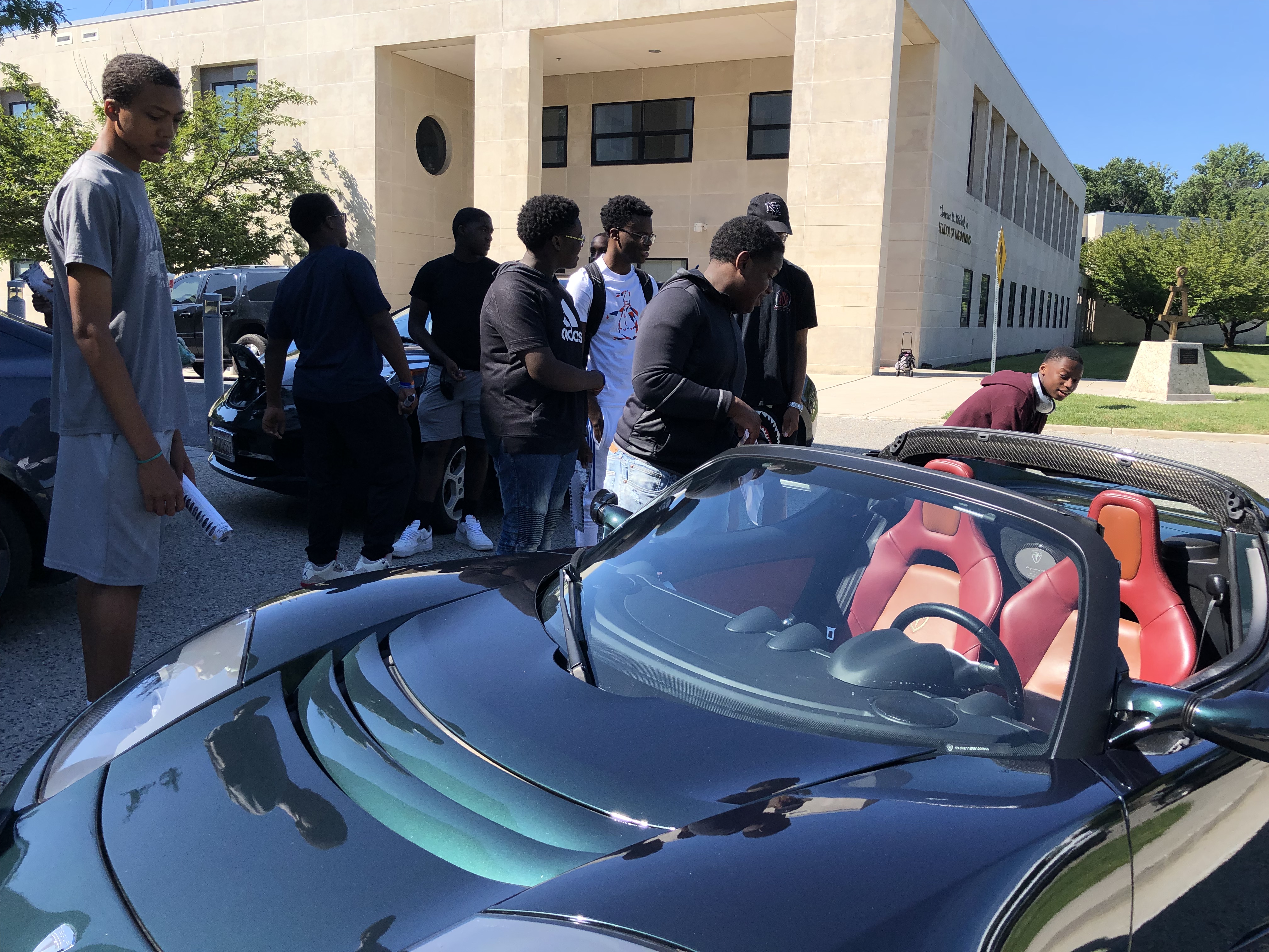 students looking at EV car