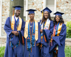 Four Morgan students in their cap and gowns